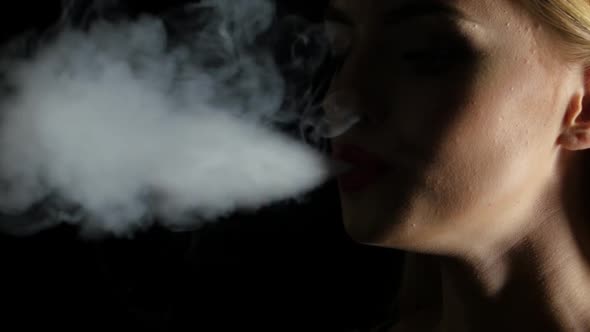 Girl Smokes an Electronic Cigarette. Black Background. Close Up. Silhouette