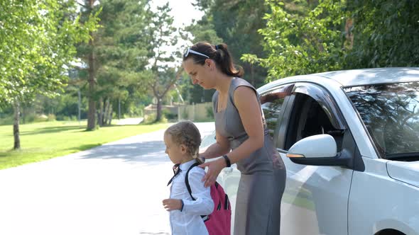 Mother Helps to Put Schoolbag on Child Outdoors