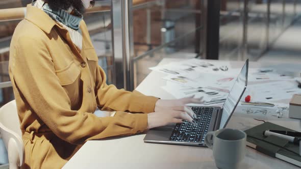 Female Designer Typing on Laptop at Desk in Fashion Studio