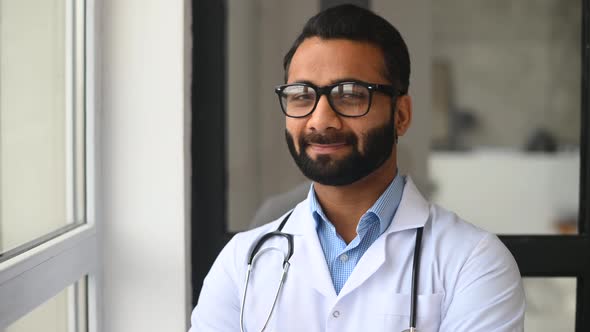 Indian Male Doctor Looking Through the Window Thoughtfully Then Turn and Looks at Camera