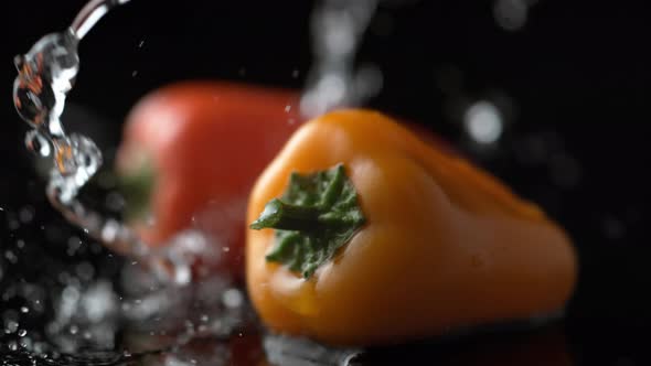 Water splash on yellow and red pepper. Slow Motion. alt