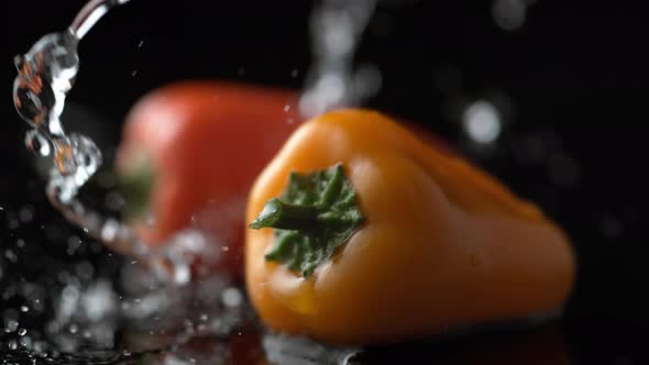 Water splash on yellow and red pepper. Slow Motion.