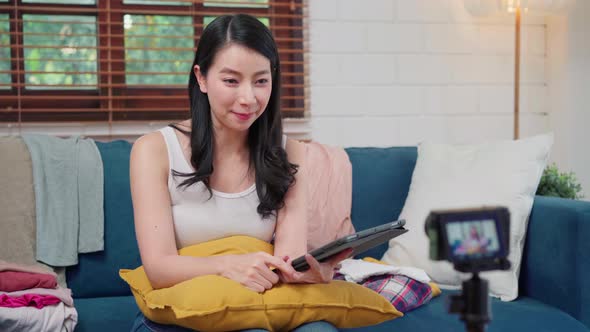 Asian fashion influencer designer women using camera streaming and live to sell clothes business.