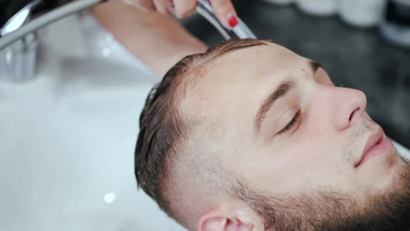 Hairdresser Washing Client's Head in White Sink in Beauty Salon