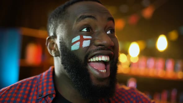 Joyful Black Soccer Fan With English Flag Painted on Cheek Celebrating Victory