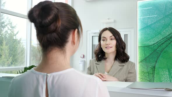 Pretty Woman Patient Talks to Administrator Near Counter