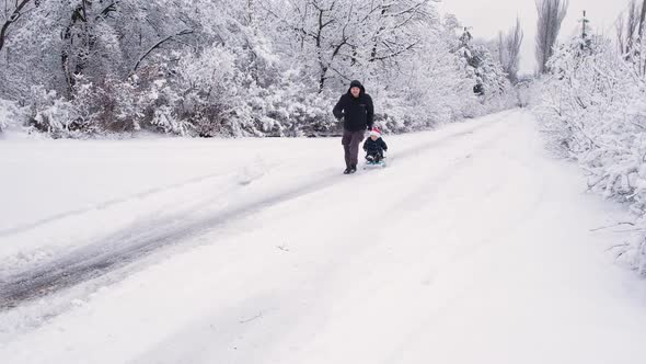 Dad Sledding His Son at a Ski Resort in a Snowcovered Winter Forest