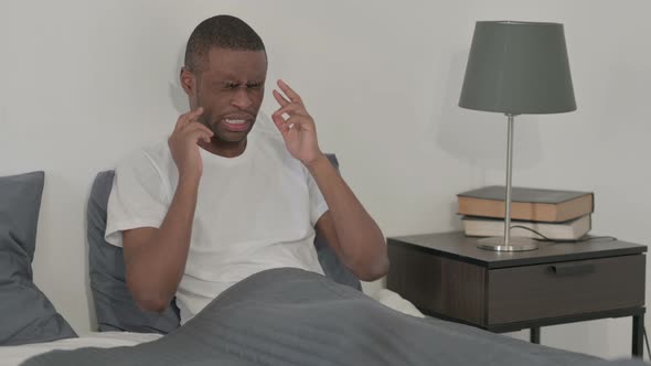 African Man Having Headache While Sitting in Bed