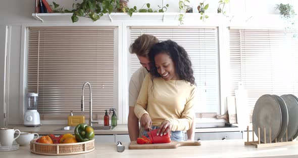 Young Multiethnic Couple Cooking Affectionately in an Apartment Kitchen