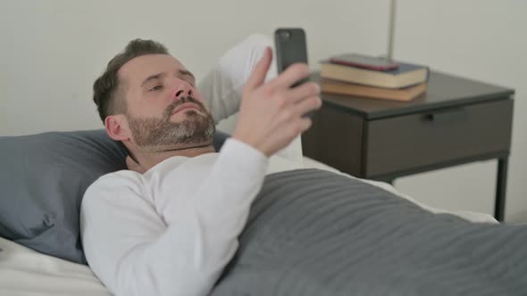 Man Using Smartphone in Bed