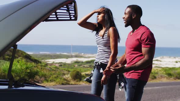 African american arguing with each other while trying to fix the car on road