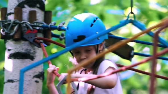 Rope Adventure in the Park - a Little Girl Moving Over the Rope Bridge