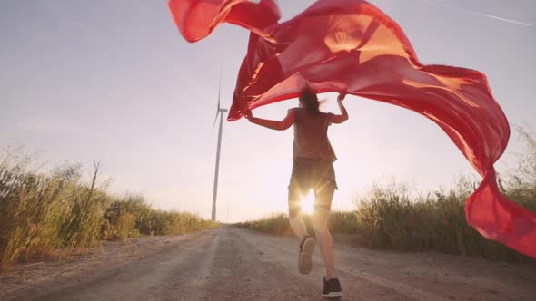 Woman with Pieces of Red Cloth Run to the Wind Generator in the Field