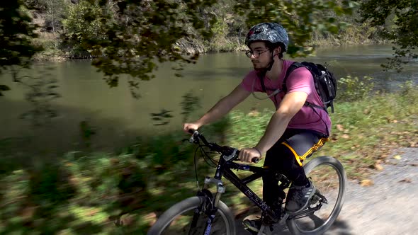 Closeup of teen boy on a mountain bike wearing a helmet and glasses with a river in the background b