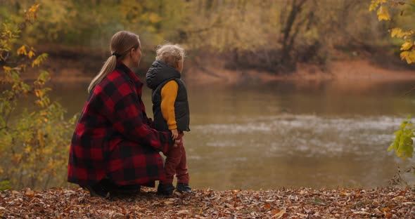 Family Rest in Autumn Forest, Mother and Little Son Are Viewing Lake, Standing on Coast with Dry