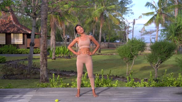 Active Young Woman Trainer Doing Exercises in the Fresh Air Tropics Palm Trees Path on the Resort