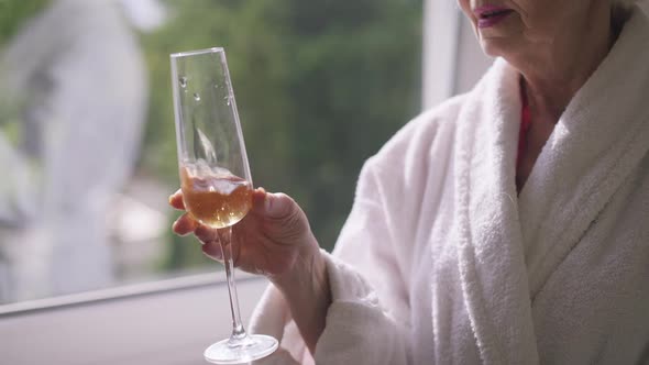 Unrecognizable Senior Caucasian Woman Shaking Glass Drinking Champagne in Slow Motion