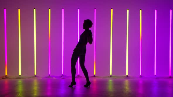 Woman Dancer Performing Street Dance in the Studio Against the Backdrop of Bright Neon Lamps in Slow