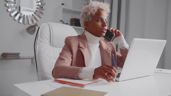 African American Business Woman Conducts Phone Negotiations Sits at Office Desk