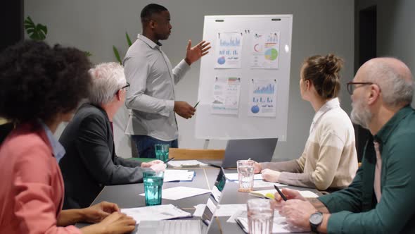 Young Black Man Giving Business Presentation to Team at Office Meeting