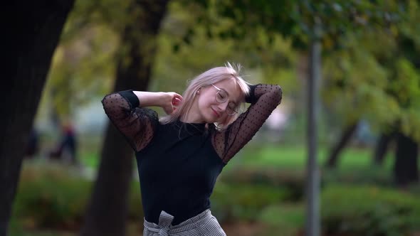 Slow Motion Portrait of Young Woman in City Park at Autumn Day, Lady Is Playing with Her Hair