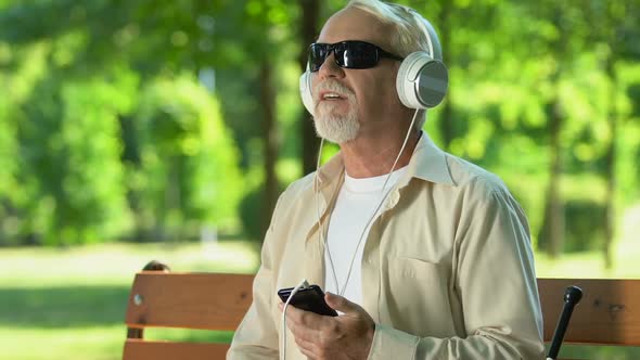 Senior Man With Visual Impairments Enjoying, Listening to Music in Headphones