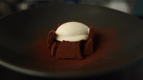 Serving chocolate brownie dessert decorated with ice cream in a professional restaurant kitchen