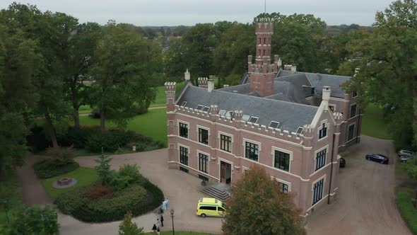 Close aerial of people assembling on front of beautiful mansion on green estate