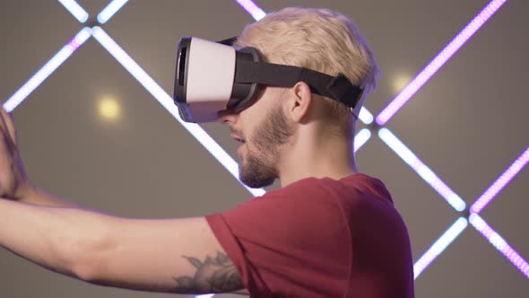 Side View of Excited Young Man in VR-glasses Touching Invisible Wall. Close-up of Cheerful Smiling