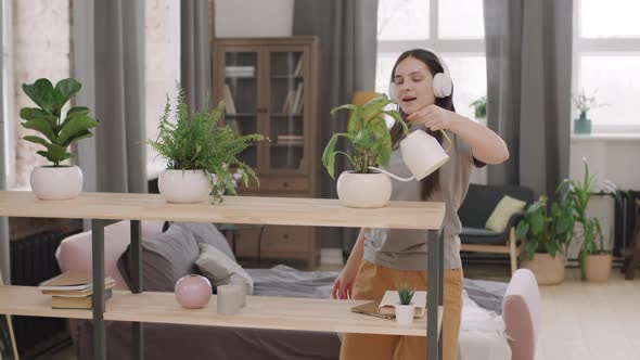 Woman Dancing to Music and Watering Plants