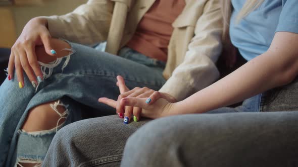 Two Attractive Girls are Sitting in the Living Room on the Sofa Talking to Each Other Holding Hands