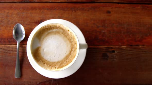 Cup of coffee with saucer and spoon on table