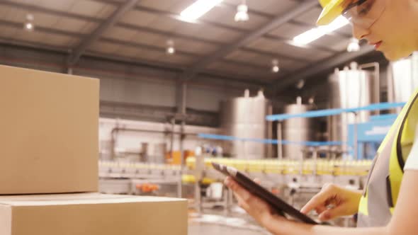 Worker maintaining record on digital tablet while cardboard boxes