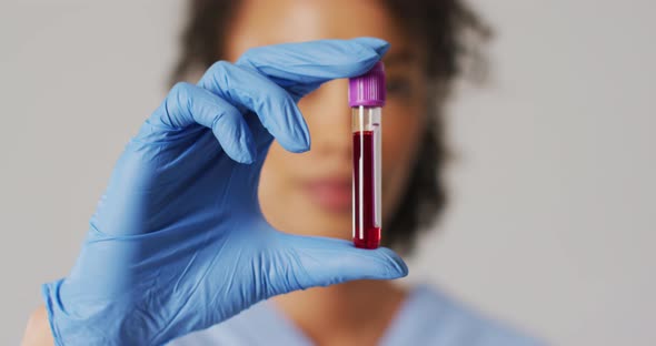 Video of biracial female doctor holding test tube on blue background