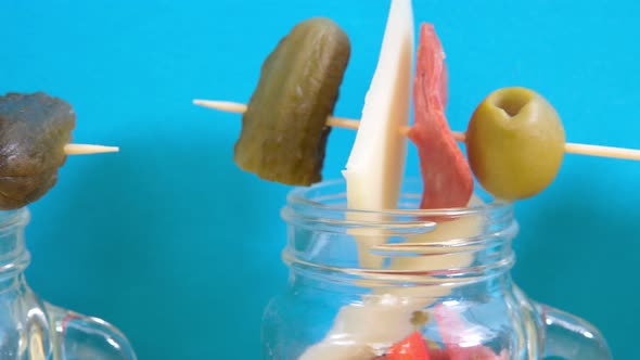 Snacks in Transparent Jars Jarcuterie Cheese Ham Salad Cucumbers Nuts on a Colorful Background