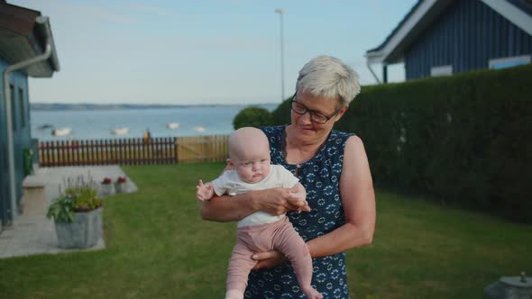 Grandmother Holding Baby Girl In Garden