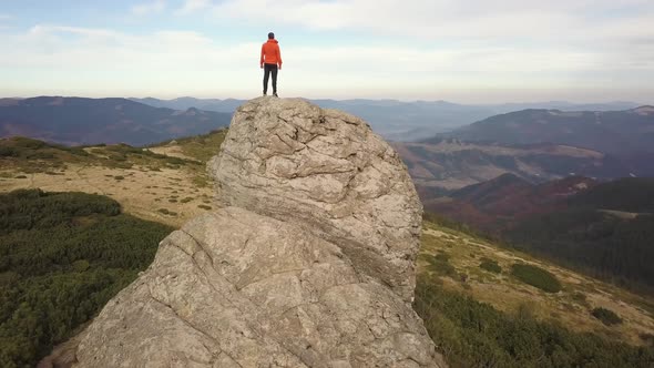 Aerial view of a hiker man climbing big rock in mountains.