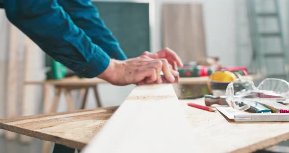 A Bearded Handyman is Sanding Wood for Furniture in a Carpentry Workshop