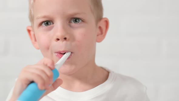 Portrait Happy Smiling Child Kid Boy Brushing Teeth with Electric Toothbrush on White Brick