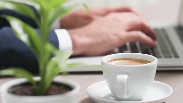 Coffee Cup in Front of Businessman Hands Typing