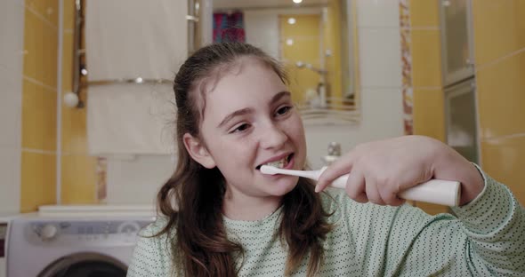 Girl Brushing Her Teeth with an Electric Toothbrush. Fron View
