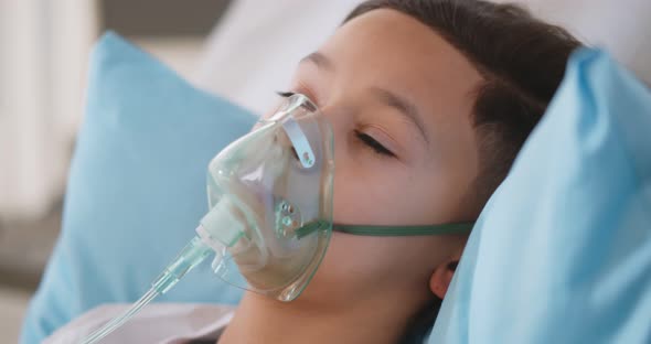 Sick African Boy Wearing Oxygen Mask Lying in Hospital Bed