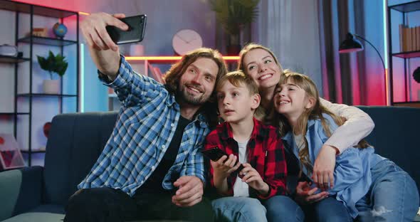 Family Sitting Together on the Sofa at Home in the Evening and Making Selfie on Smartphone