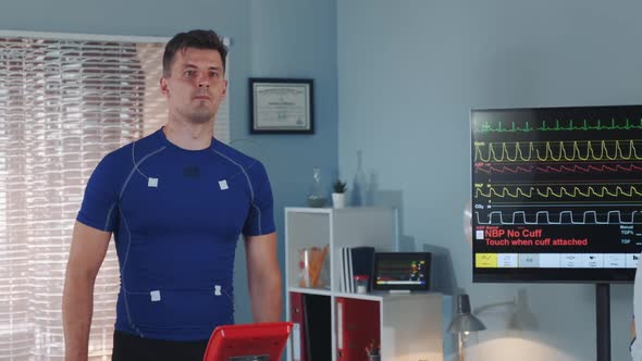 Middle Close-up of Athlete Walking on Treadmill and Female Doctor Coming To Monitor the Process alt