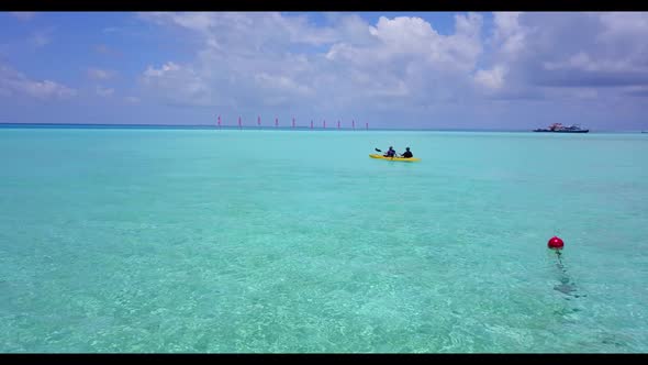 Young couple sunbathing on relaxing island beach vacation by transparent ocean and white sandy backg