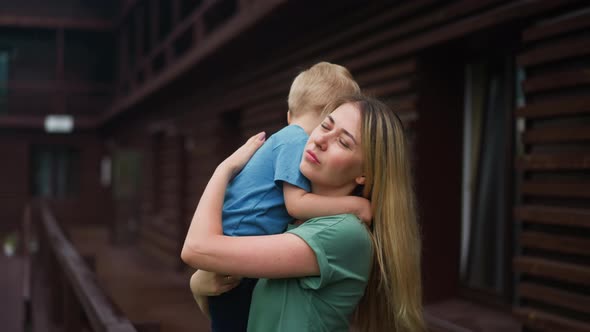 Mother Calms Down Upset Weepy Toddler Son on Veranda Deck