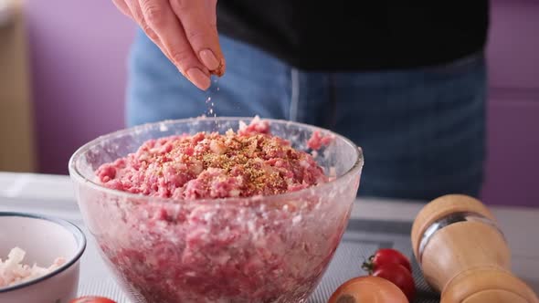 Adding Salt and Spices to Minced Meat with Onion and Spices in a Glass Bowl Making Cutlets