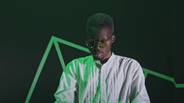 Positive Handsome Guy in White Shirt, Sunglasses Having Fun on Black Background. Listening To Music