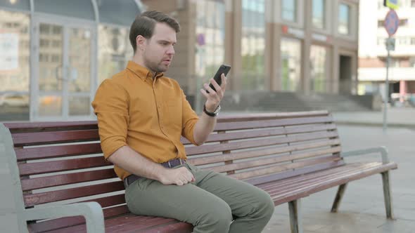 Upset Young Man Reacting to Loss on Smartphone Outdoor