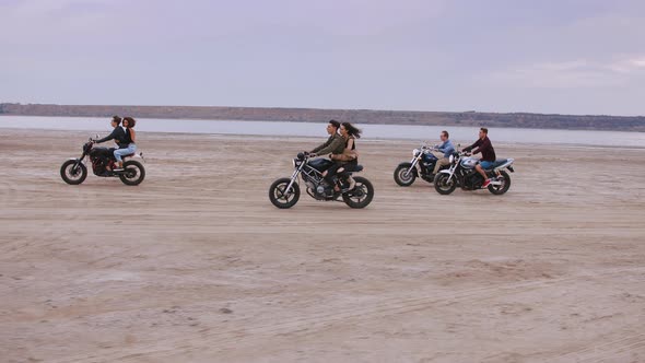 Group of Young People Riding Motorbikes on the Beach in Evening